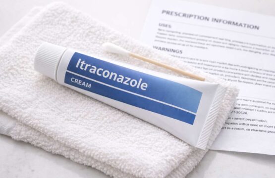 Tube of itraconazole cream and cotton swab on a clean towel next to a prescription leaflet.