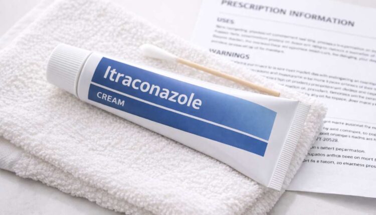 Tube of itraconazole cream and cotton swab on a clean towel next to a prescription leaflet.